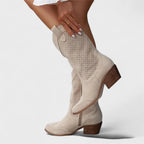 Side view of beige suede mid-calf western boot with perforated panel detail and stacked block heel