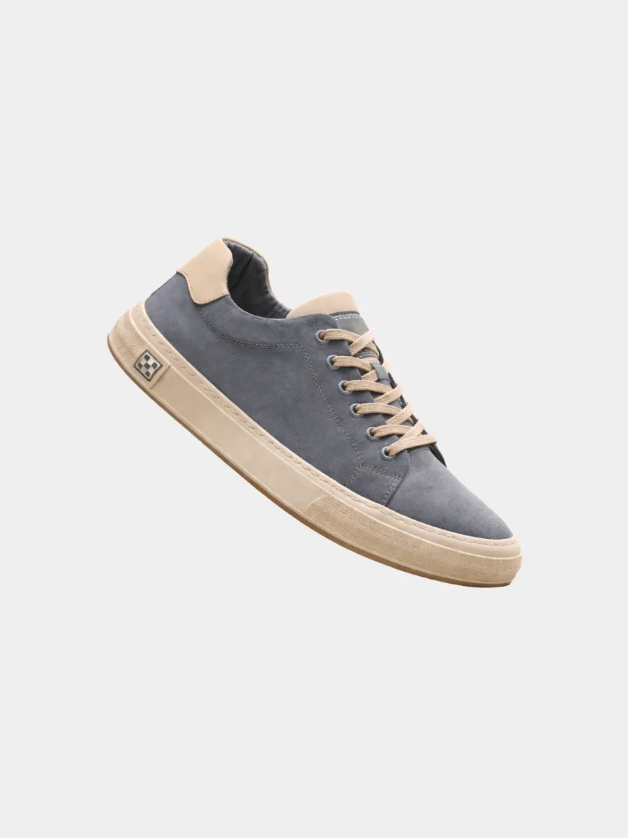 Side view of a blue suede low-top trainer with beige laces, cream sole and a checkered side tab