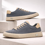 Pair of blue suede trainers with beige soles and tan laces displayed on a stepped concrete surface