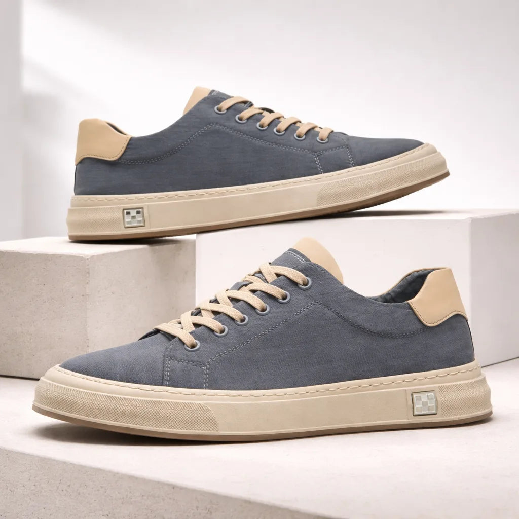 Pair of blue suede trainers with beige soles and tan laces displayed on a stepped concrete surface