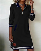 Model wearing beige sweatshirt dress with both hands tucked into the front welt pockets