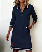 Cream sweatshirt dress styled with layered gold necklaces and a wristwatch, front-facing pose