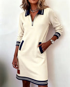 Close-up of beige/off-white sweatshirt dress showing polo collar, quarter-zip and navy striped cuff detail on the sleeve