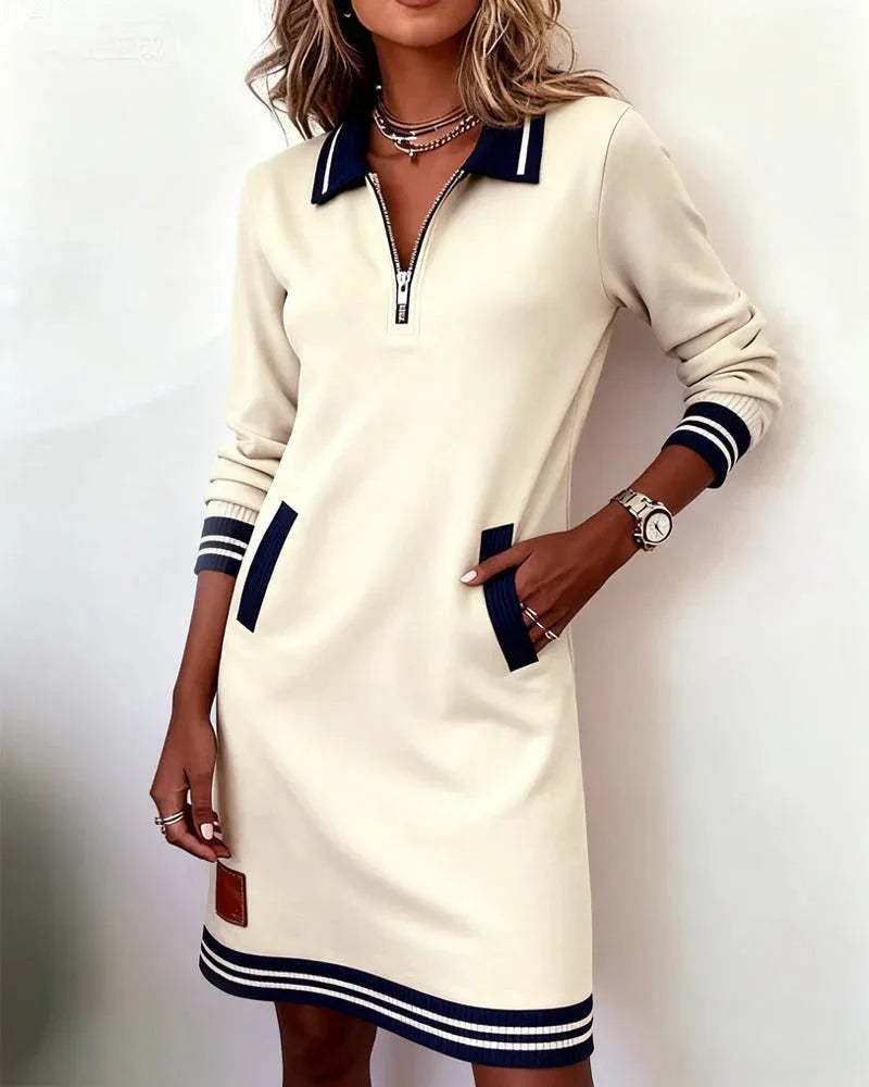 Close-up of beige/off-white sweatshirt dress showing polo collar, quarter-zip and navy striped cuff detail on the sleeve