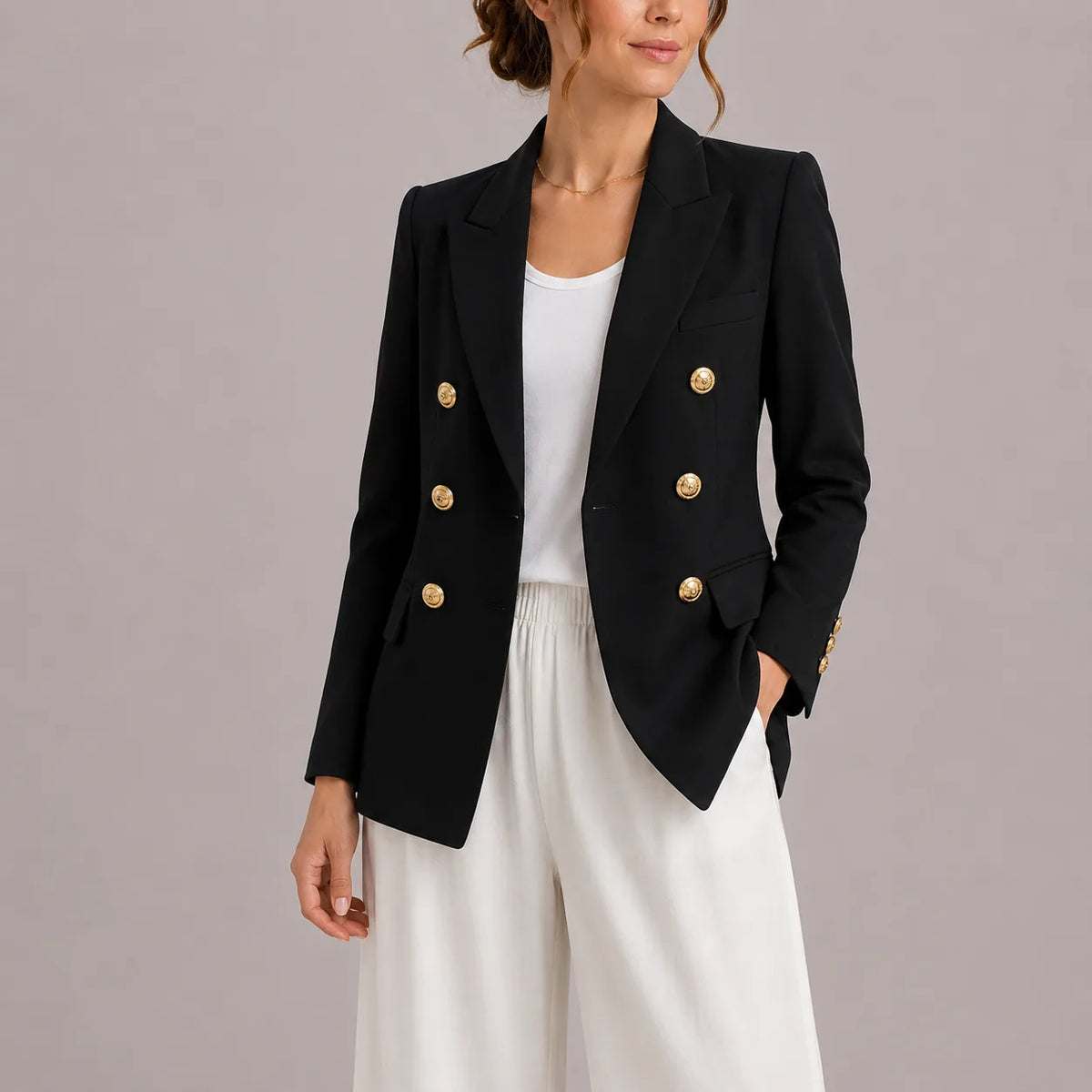 Black double-breasted blazer with gold-tone buttons and peak lapel, worn open over a white top