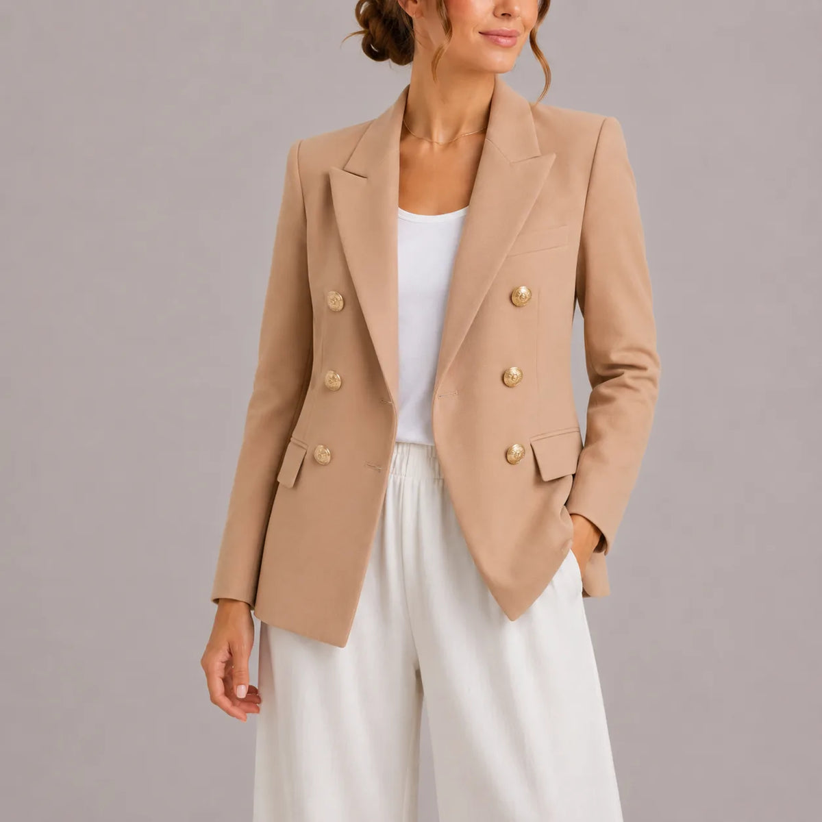 Beige double-breasted blazer with gold buttons, close-up of tailored lapel and shoulder