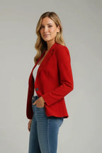 Side profile of a woman in a red notched-lapel blazer paired with denim jeans