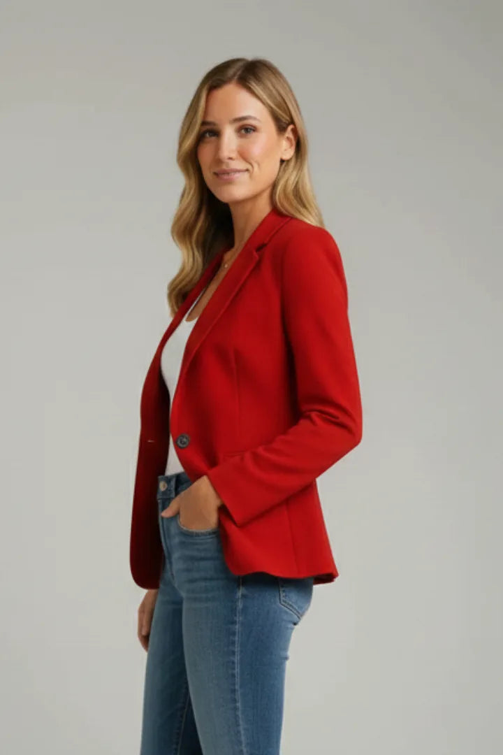 Side profile of a woman in a red notched-lapel blazer paired with denim jeans