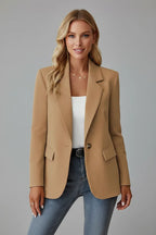 Woman wearing a camel-coloured tailored blazer with a single button over a white top and jeans