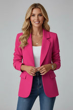 Woman wearing a hot pink tailored blazer with notched lapel, hands clasped at the waist