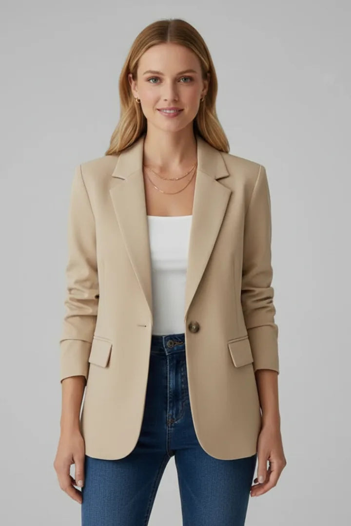 Woman wearing a beige single-button blazer with flap pockets over a white top and denim