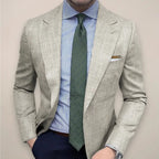 Close-up of a man in a beige textured blazer worn with a striped blue shirt and green patterned tie