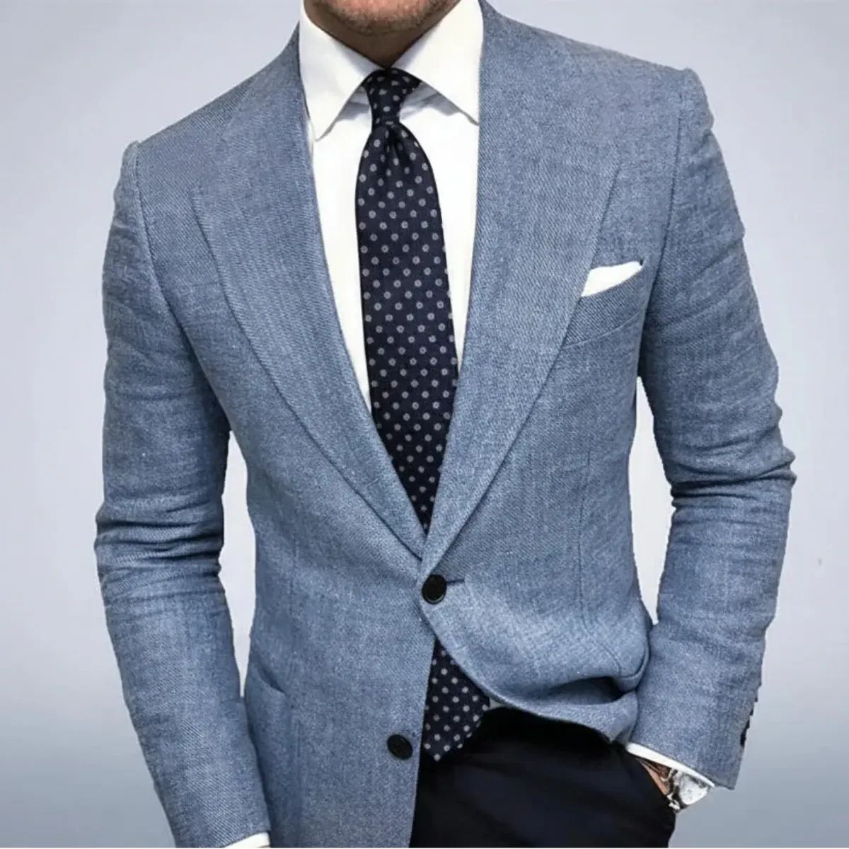 Close-up of a light blue textured blazer paired with a white shirt and navy polka dot tie