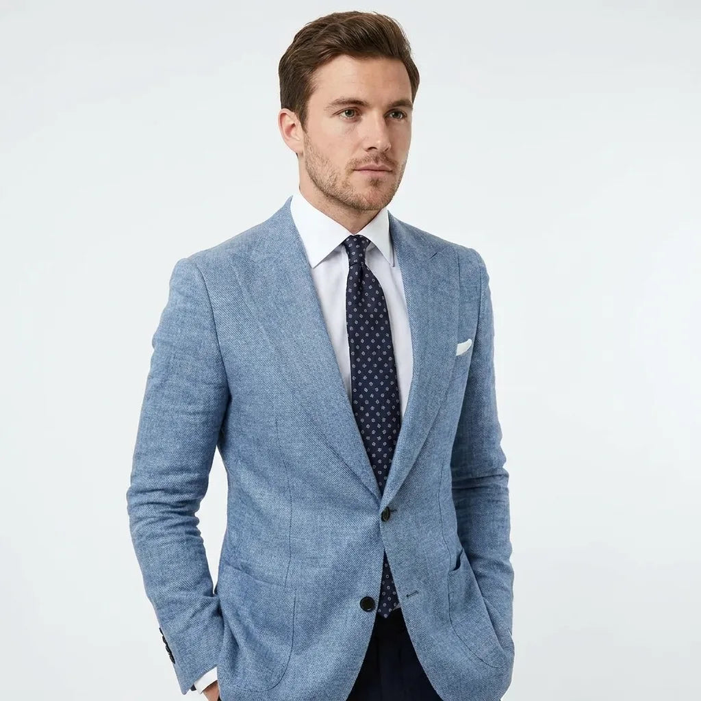 Three-quarter view of a blue textured blazer with peak lapel, white shirt and spotted navy tie