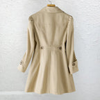 Back view of a beige trench-style coat on a wooden hanger, showing puffed shoulder seams and a fitted waist with button tabs