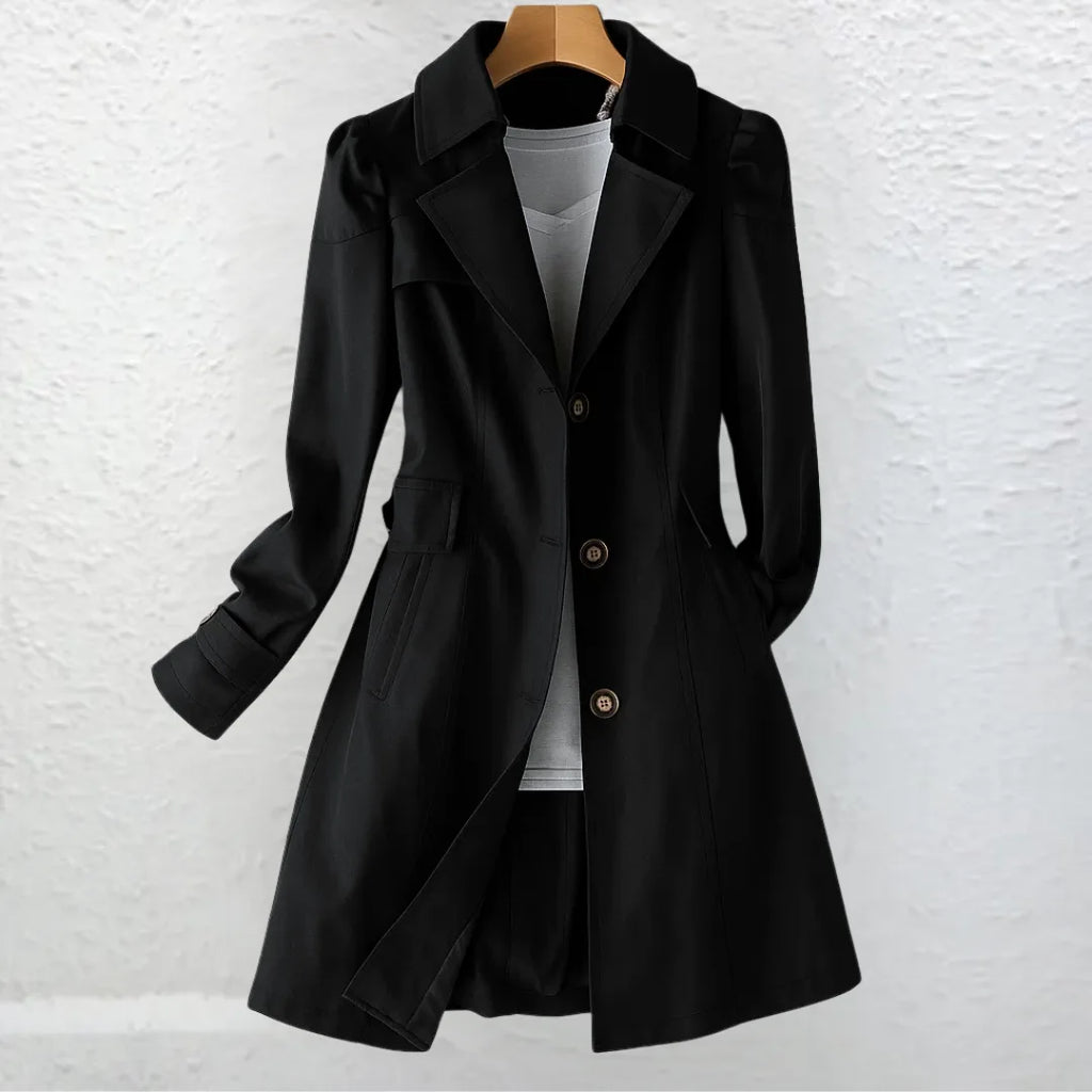 Black tailored trench coat worn open over a grey top, showing notched lapel collar and single-breasted button front