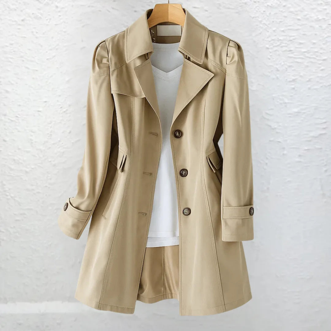 Khaki trench coat worn open over a white top, showing structured lapels, side pockets and buttoned cuff detail