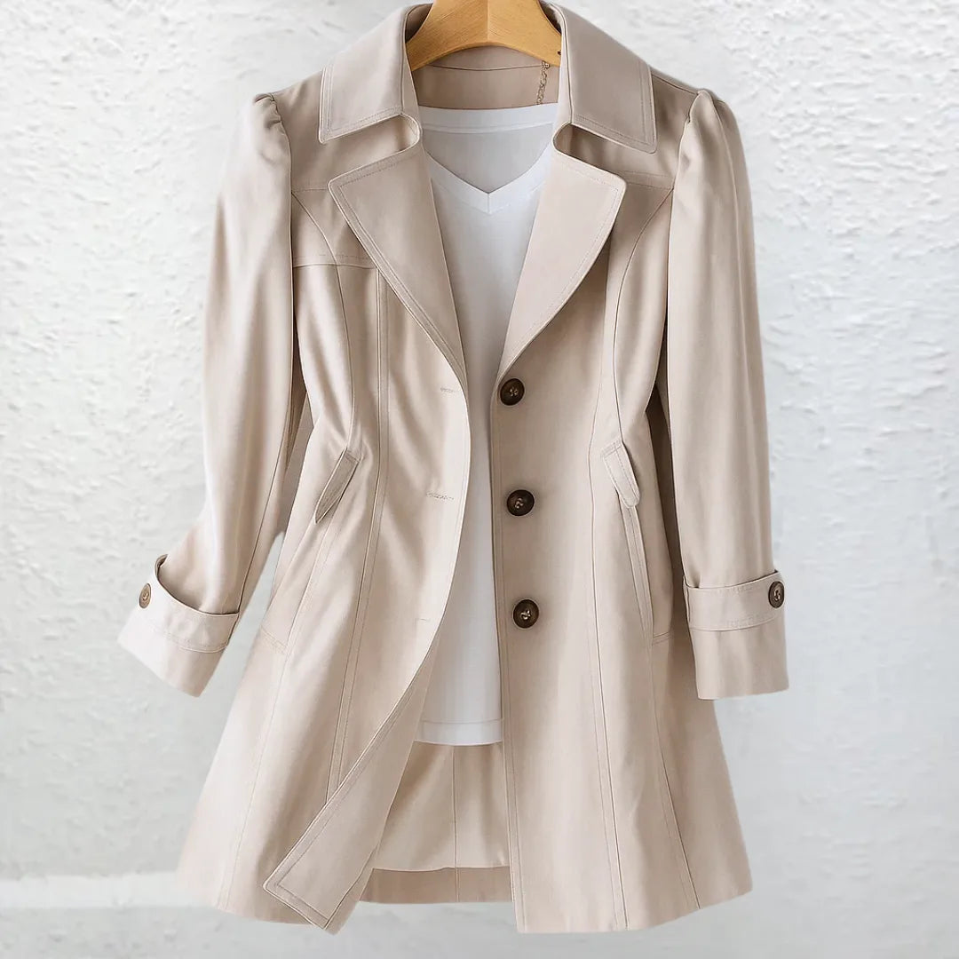 Close-up front view of a beige trench coat on a hanger, highlighting the wide collar, puff-shoulder seams and button cuffs