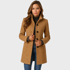 Woman in a camel wool-blend coat with stand collar, button front and patch pockets, worn open over a brown polo neck