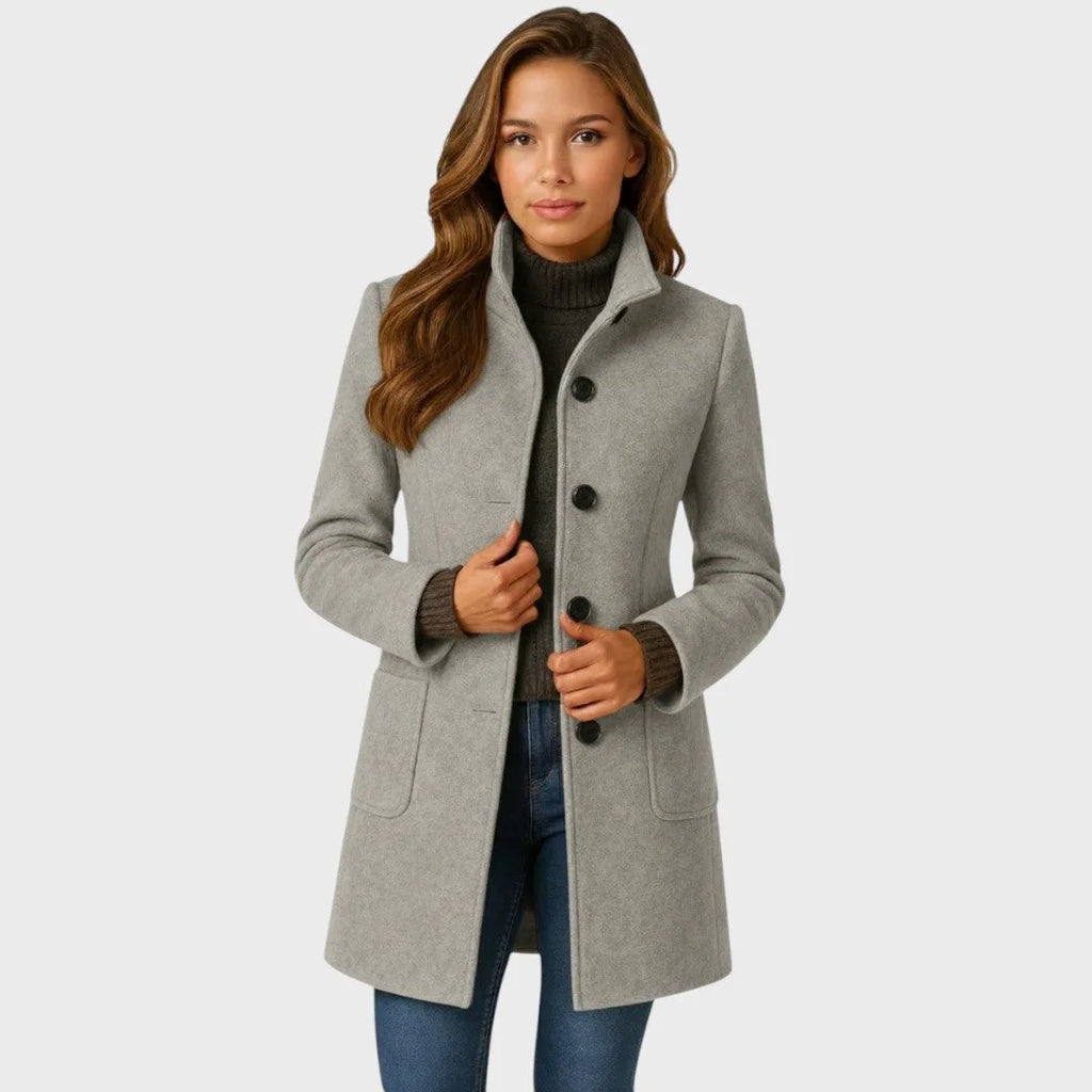 Light grey wool-blend coat with stand collar and button-up front, worn open over a brown polo neck jumper
