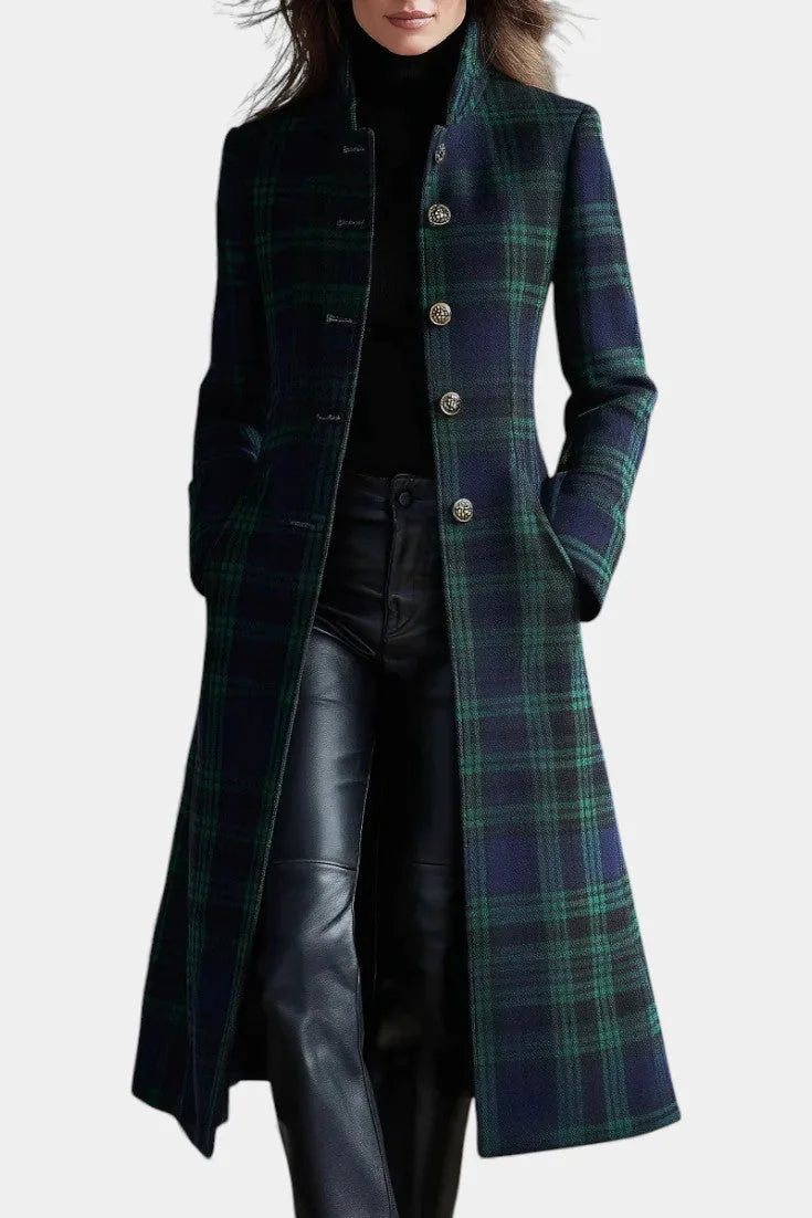Front view of a woman wearing a green and navy tartan longline coat with stand collar over a black polo neck