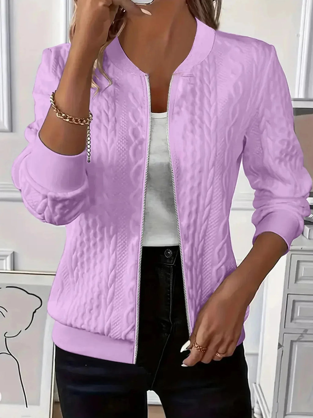 Model wearing pink textured bomber jacket over a white top with black trousers, front detail view