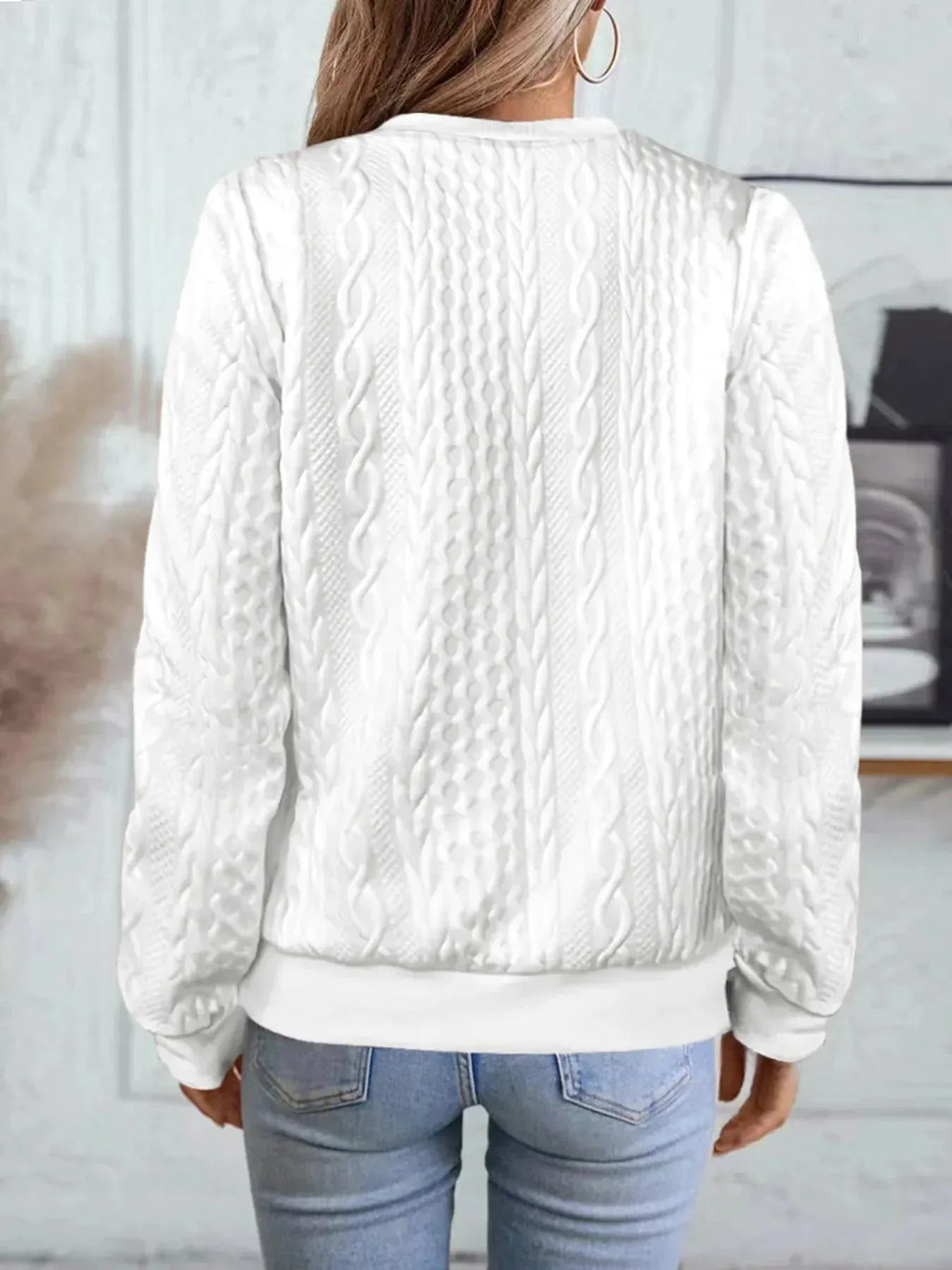 Back view of white textured bomber jacket showing cable knit pattern across shoulders and ribbed hem