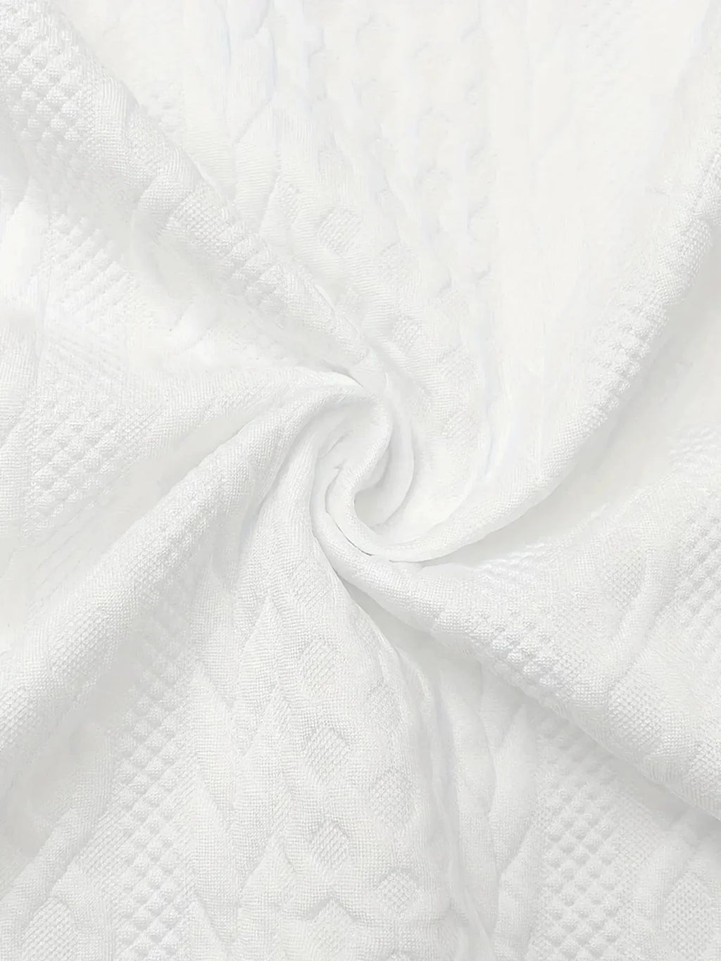 Close-up of white knit-textured fabric swirled to show its dimensional cable pattern and softness
