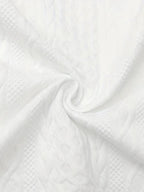 Close-up of white knit-textured fabric swirled to show its dimensional cable pattern and softness