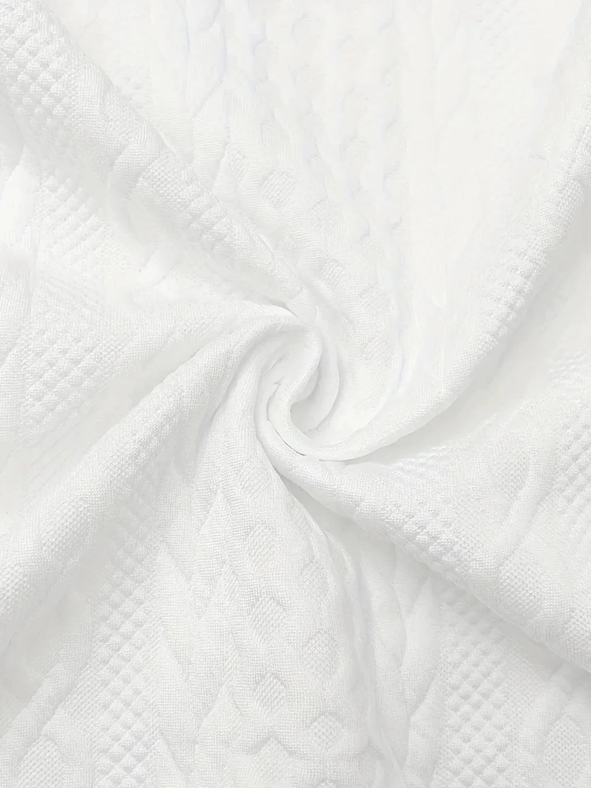 Close-up of white knit-textured fabric swirled to show its dimensional cable pattern and softness