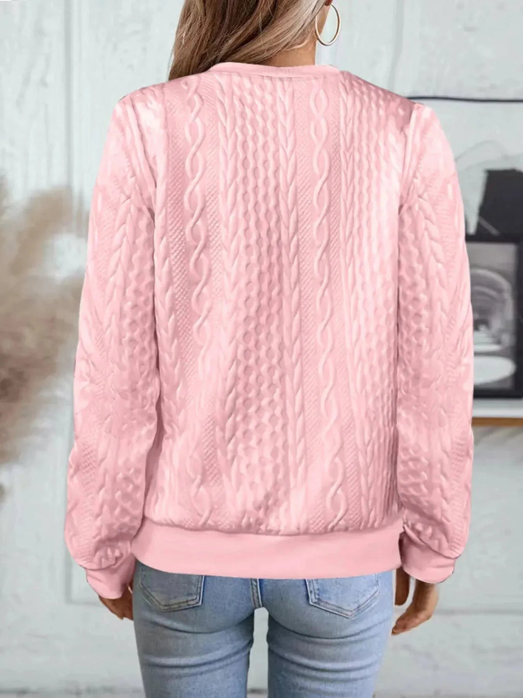Back view of pink textured bomber jacket highlighting cable knit design and ribbed cuffs