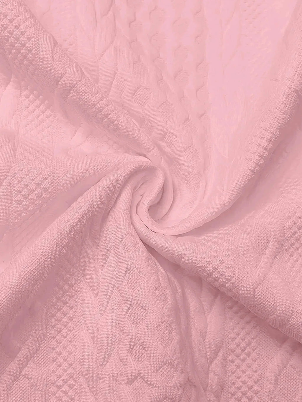 Close-up of pink textured fabric swirled to display the raised cable knit pattern in detail