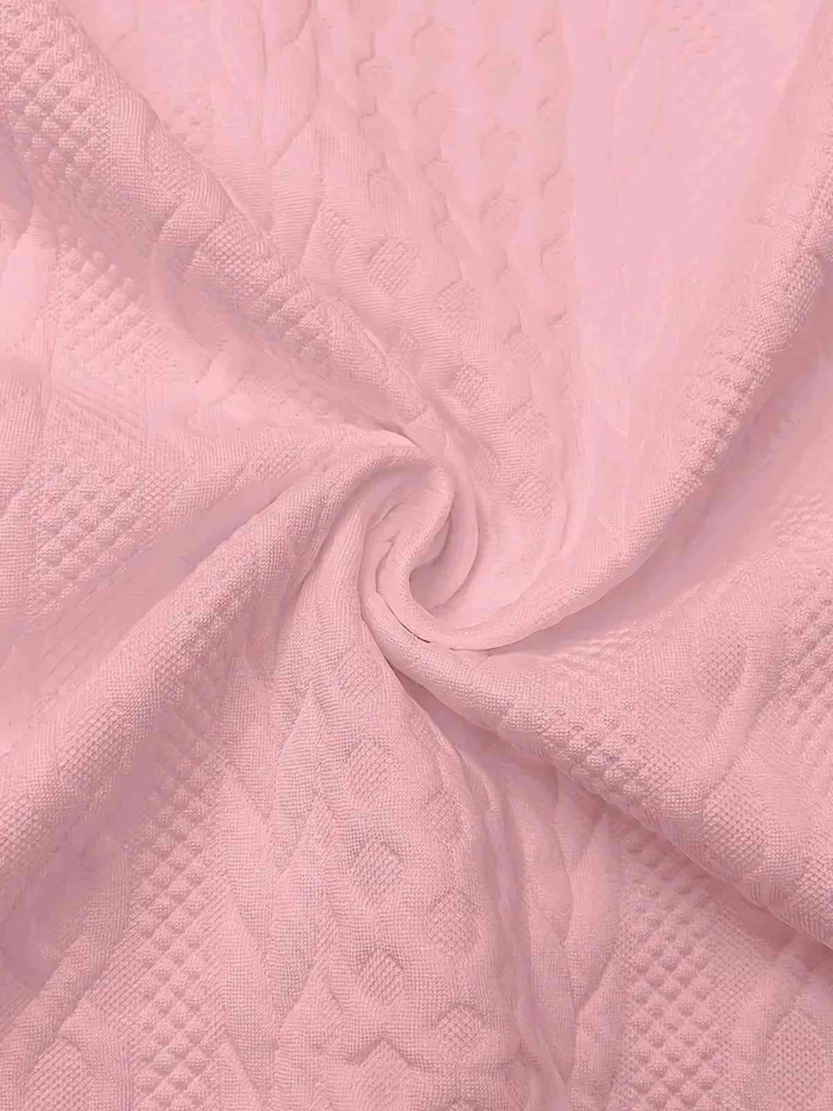Close-up of pink textured fabric swirled to display the raised cable knit pattern in detail