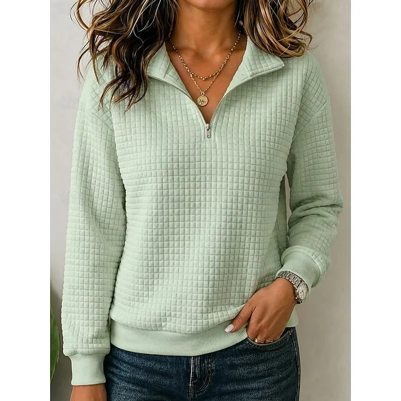 Close-up front view of a light green textured quarter-zip pullover with stand collar and layered gold necklace
