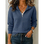 Front view of a navy blue textured quarter-zip pullover layered over a lace-trim top