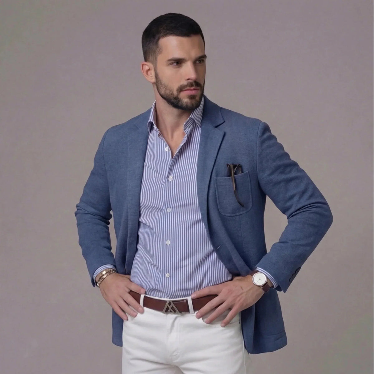 Side angle of man standing with hands on hips wearing a blue textured blazer and striped shirt