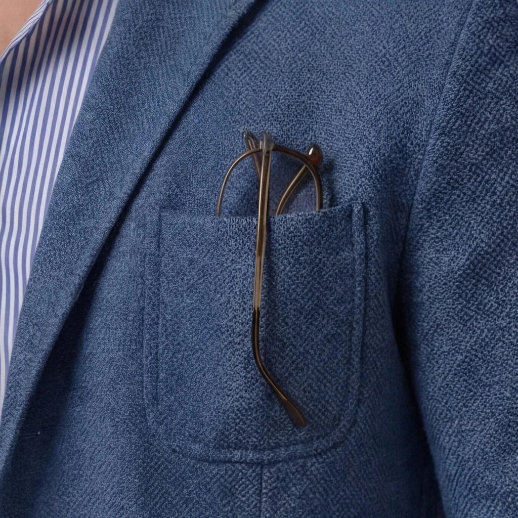 Close-up of the chest pocket with glasses tucked in, showing the woven texture of the blue fabric