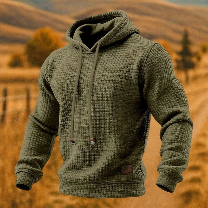 Army green textured waffle-knit pullover hoodie with drawstring hood, shown front on a model outdoors