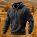 Dark grey waffle-knit pullover hoodie shown from a slight side angle highlighting the hood shape