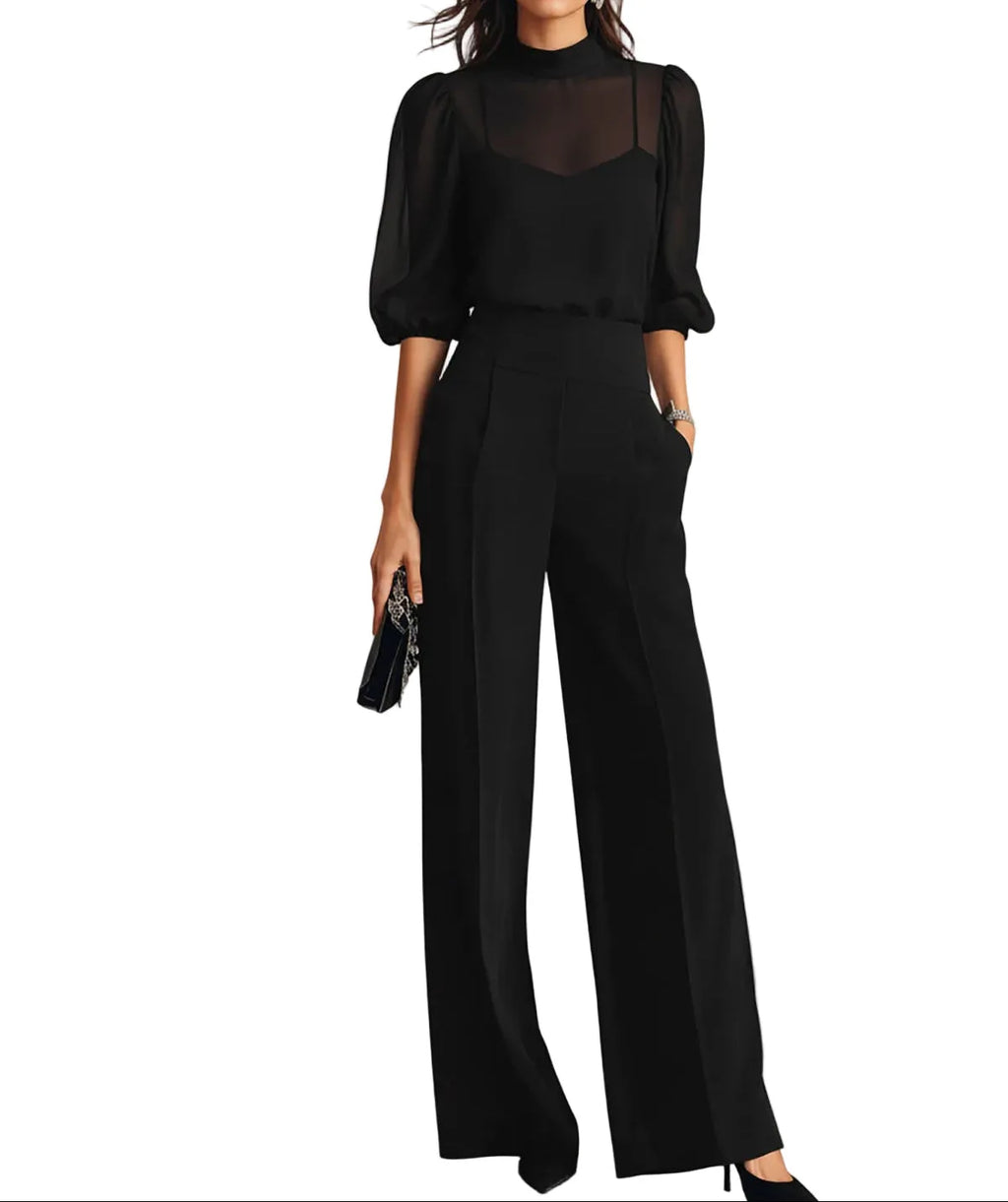 Woman wearing a black three-piece set with sheer mock-neck blouse, pleated wide-leg trousers and pointed heels