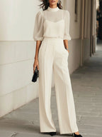Three-piece set in white, showing the sheer puff-sleeve top layered over a camisole with matching wide-leg trousers
