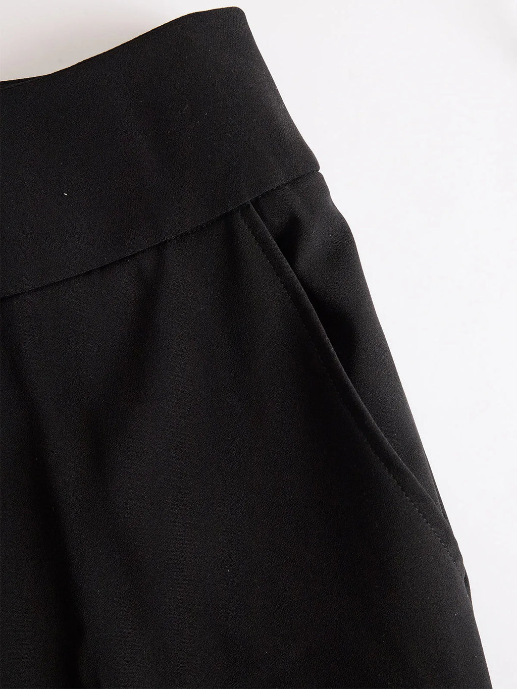Close-up of the black trousers' high waistband and side pocket with visible seam detail