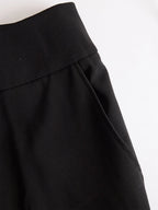 Close-up of the black trousers' high waistband and side pocket with visible seam detail