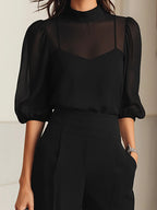 Close-up of the black sheer mock-neck blouse showing the camisole underlayer and puff sleeves