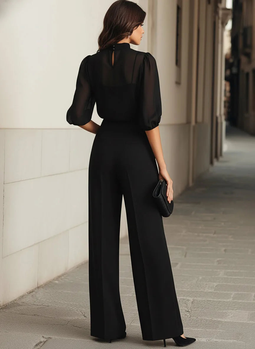 Front view of the black outfit focusing on the trousers' clean tailored silhouette and wide leg