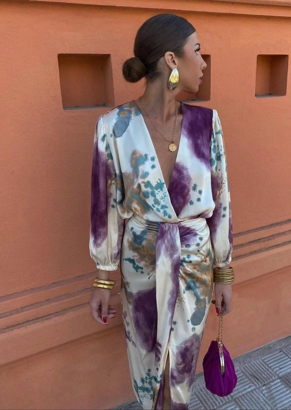 Side profile of the wrap dress highlighting the draped tie waist, gold bangles and teardrop earrings