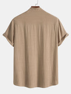 Reverse view of beige stand-collar shirt showing back yoke and rolled sleeve cuffs