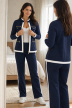 Front view in a mirror showing the navy jacket's stand collar, gold zip and flap pockets with matching straight-leg trousers