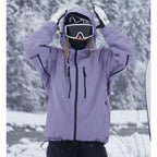 Close-up front view of a lilac purple ski jacket with hood pulled up and both hands raised to the hood