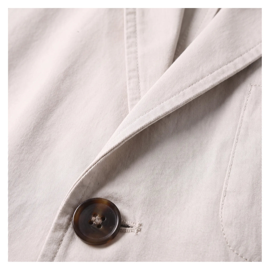 Close-up of the tortoiseshell-effect button and notch lapel stitching on the beige cotton blazer